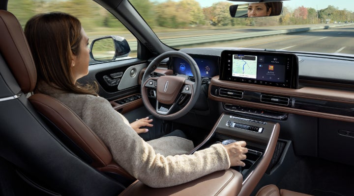 A 2026 Lincoln Aviator® SUV is being driven hands-free on a highway near a forest | Lincoln of Wayne in Wayne NJ