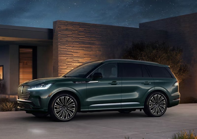 A green 2027 Lincoln Aviator® SUV is parked outside a contemporary home. | Lincoln of Wayne in Wayne NJ