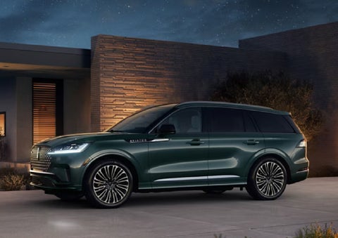 A green 2027 Lincoln Aviator® SUV is parked outside a contemporary home. | Lincoln of Wayne in Wayne NJ