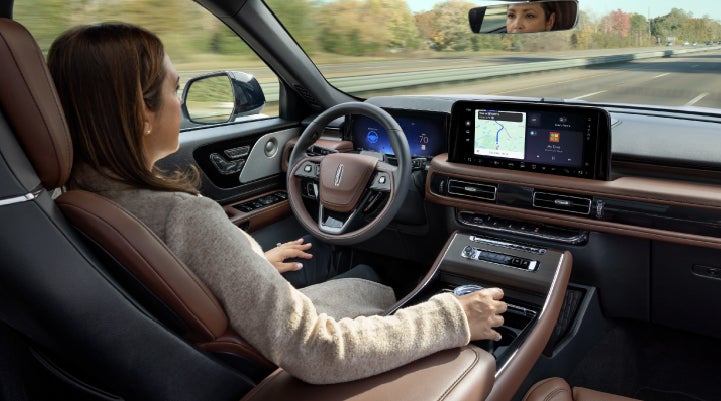A 2027 Lincoln Aviator® SUV is being driven hands-free on a highway lined with trees. | Lincoln of Wayne in Wayne NJ