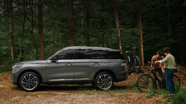 A father and son load e-bikes on a bike rack attached to a 2027 Lincoln Aviator® SUV. | Lincoln of Wayne in Wayne NJ