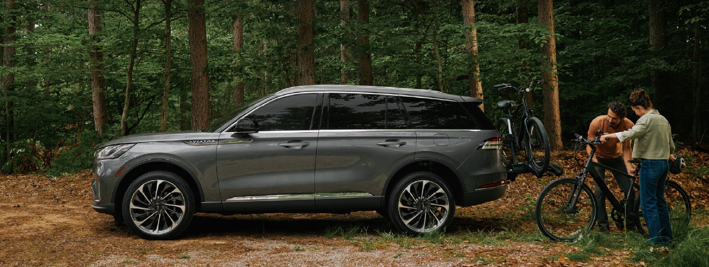 A father and son load e-bikes on a bike rack attached to a 2027 Lincoln Aviator® SUV. | Lincoln of Wayne in Wayne NJ