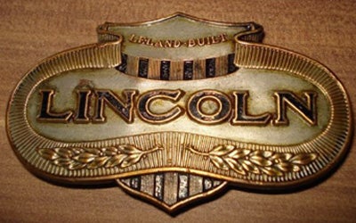 Ornate, gold and silver vintage lincoln leland built car emblem with laurel wreaths.